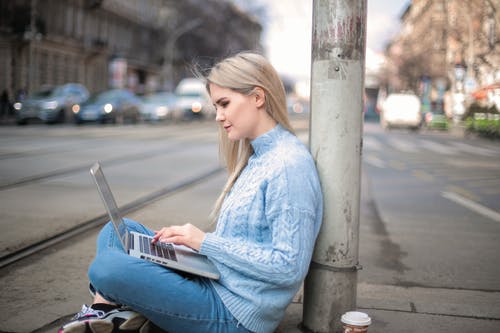 使用笔记本电脑时蓝色长袖衬衫的女人 · 免费素材图片