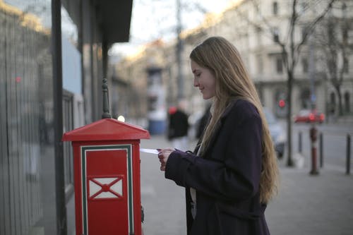 黑色外套站在红色电话亭旁边的女人 · 免费素材图片
