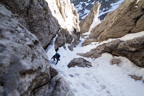 在岩石山与雪之间行走的人 · 免费素材图片
