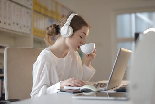 白色礼服衬衫的女人使用白色便携式计算机 · 免费素材图片