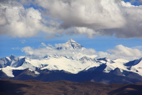 白天白雪皑皑的山在多云的天空下 · 免费素材图片