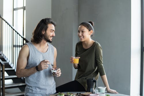 灰色背心的男人和绿色背心的女人拿着透明的水杯 · 免费素材图片