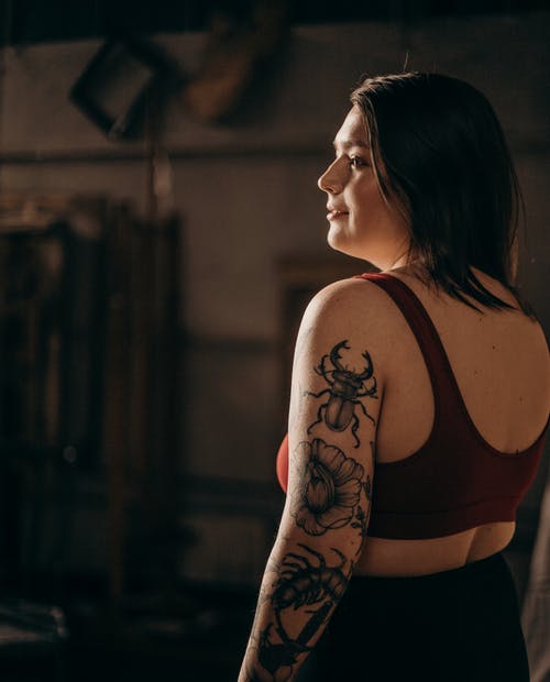 红色背心与手臂上的黑色花卉纹身的女人 · 免费素材图片