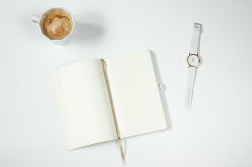 笔记本旁边的白色皮革表带银色圆形模拟手表 · 免费素材图片