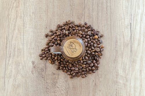 咖啡豆包围的杯子的平躺摄影 · 免费素材图片