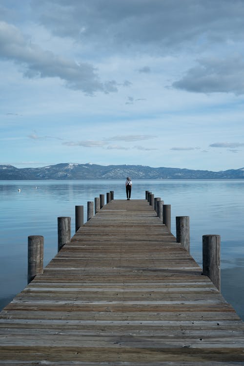 站在海上的棕色木码头上的人 · 免费素材图片