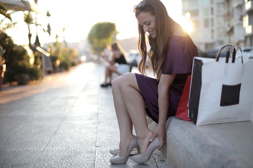女人适合她的高跟鞋坐在混凝土长凳上的浅焦点照片 · 免费素材图片