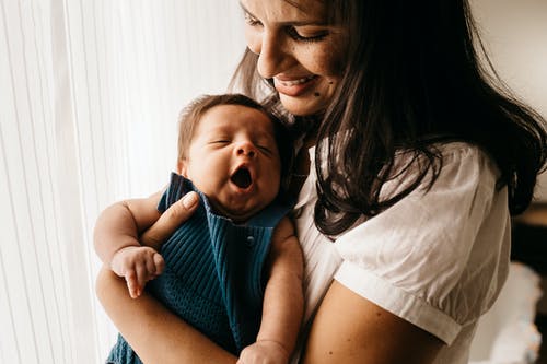 微笑的母亲抱着她可爱的婴儿的特写照片 · 免费素材图片
