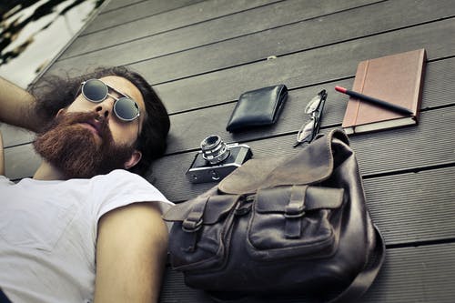 躺在黑色的木质表面上的白船员脖子t恤戴太阳镜的男人 · 免费素材图片