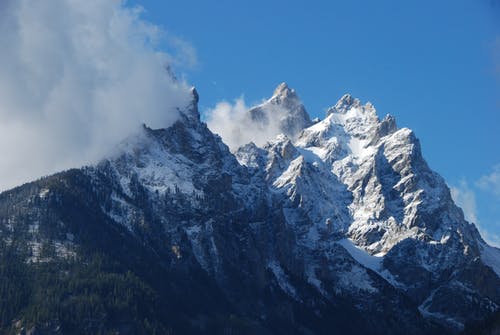 在蓝蓝的天空和云下白雪覆盖的岩石山 · 免费素材图片