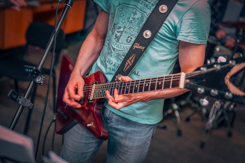 蓝色牛仔牛仔裤弹红色电吉他的人 · 免费素材图片