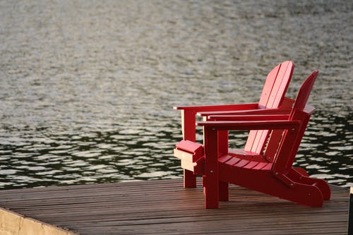 白天在水面附近的棕色木板路上的红色木制休闲椅 · 免费素材图片