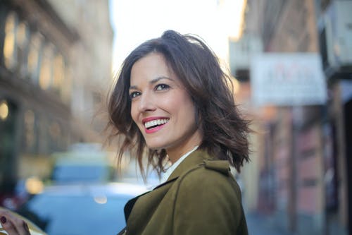 绿色外套的微笑的妇女的选择聚焦侧视图照片 · 免费素材图片