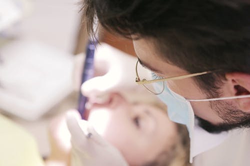 男牙医在女人的牙齿上工作 · 免费素材图片