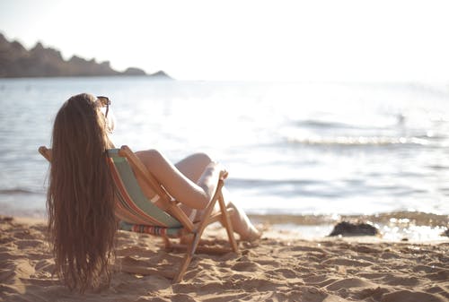 白色比基尼泳装，斜倚在沙滩椅上的女人 · 免费素材图片