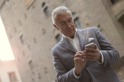 拿着智能手机的灰色西装的男人 · 免费素材图片
