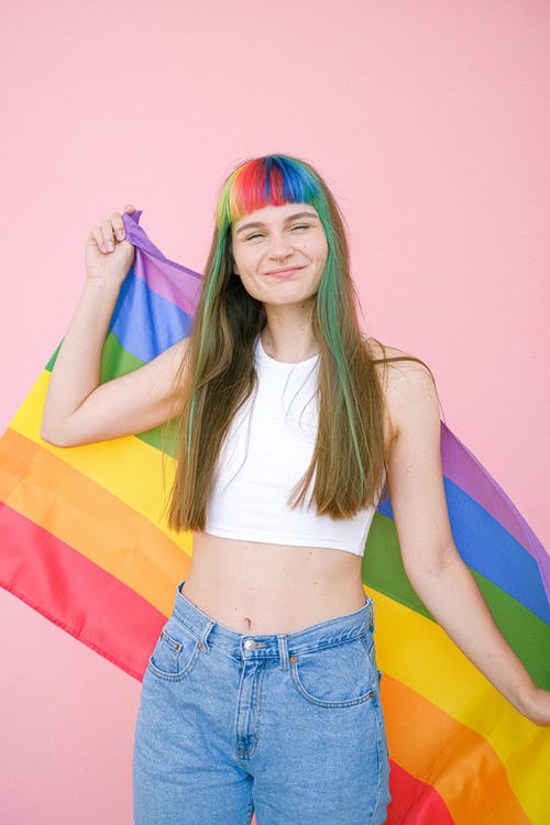 拿着同性恋骄傲旗帜的白色背心的女人 · 免费素材图片