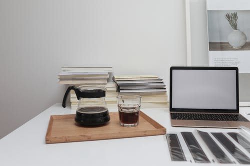 Macbook Pro旁边棕色木制的桌子上的透明水杯 · 免费素材图片
