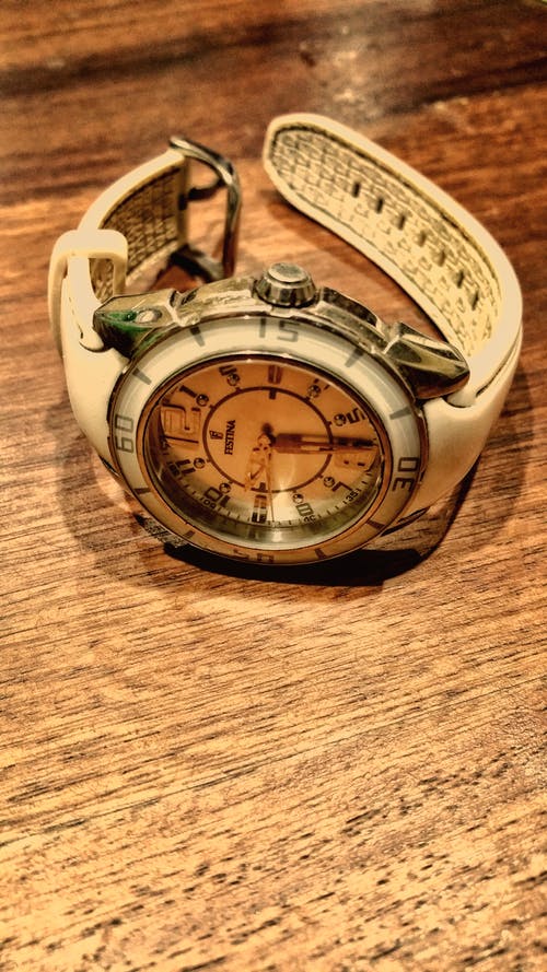 圆形银色和白色模拟手表，棕色木质表面上带有白色橡皮筋 · 免费素材图片