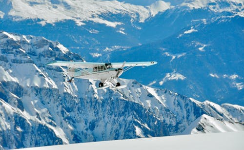 白色和绿色的单翼飞机飞过山 · 免费素材图片