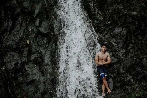 在山的快速瀑布附近的肌肉亚洲游客 · 免费素材图片