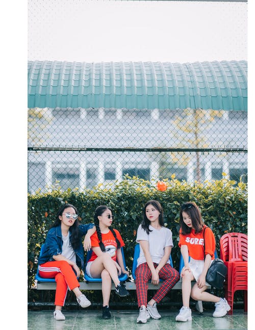 四个女孩坐在灰色的钢凳上 · 免费素材图片