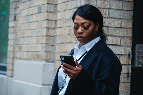 在大厦附近使用智能手机的黑人女商人 · 免费素材图片