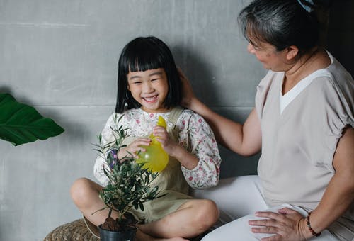有照顾植物的祖母的笑的女孩 · 免费素材图片