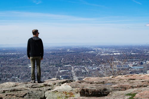 穿黑夹克站在岩石巨石上的男人 · 免费素材图片