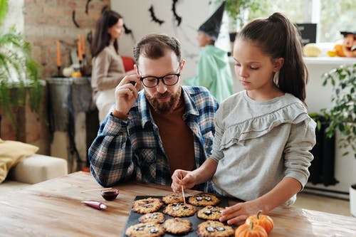 一个女孩和她父亲一起装饰饼干 · 免费素材图片