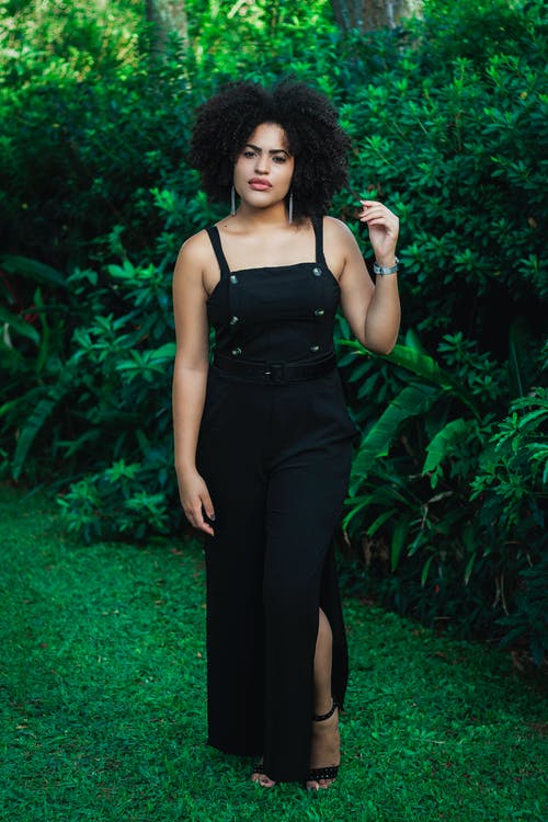 女人穿着黑色的连衣裙，站在植物旁边 · 免费素材图片