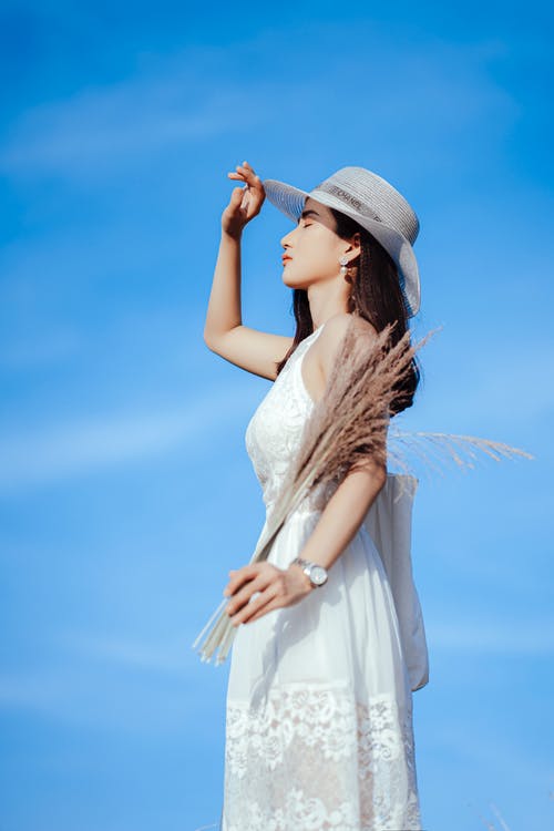 白色的裙子和白色的帽子站在蓝蓝的天空下的女人 · 免费素材图片