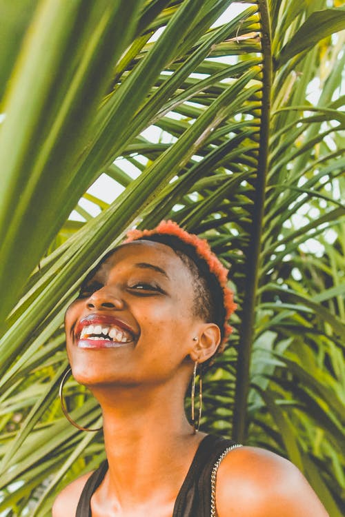 微笑在植物旁边的女人 · 免费素材图片