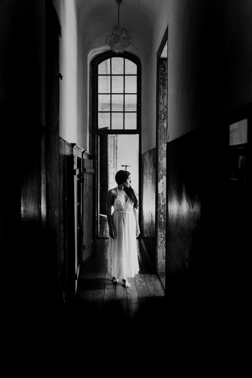 宁静的女人站在狭窄的老建筑走廊 · 免费素材图片