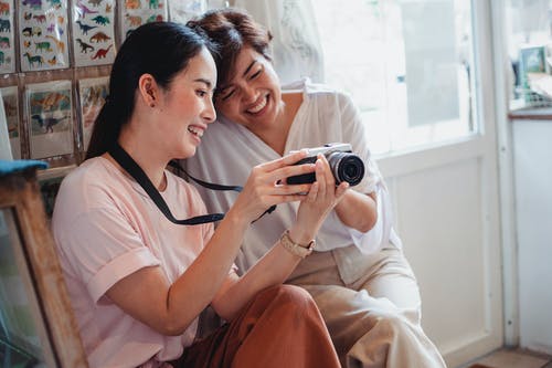 快乐的亚洲女友在商店分享相机拍照 · 免费素材图片