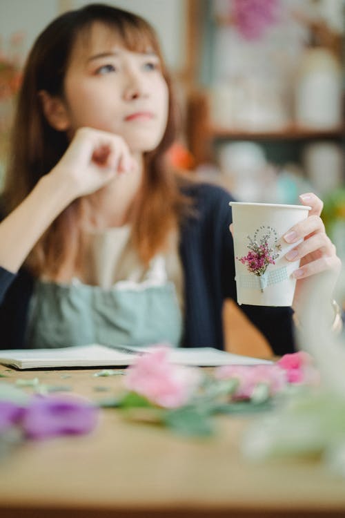 体贴的亚裔女子，在花店里的咖啡 · 免费素材图片