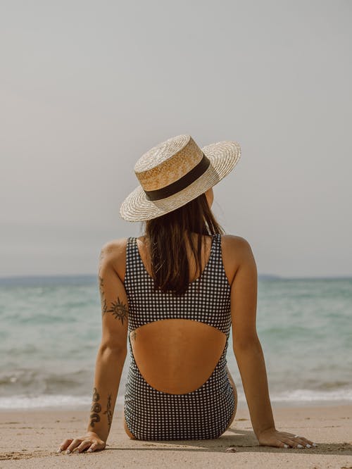 纹身在泳装和帽子在沙滩上休息的女人 · 免费素材图片