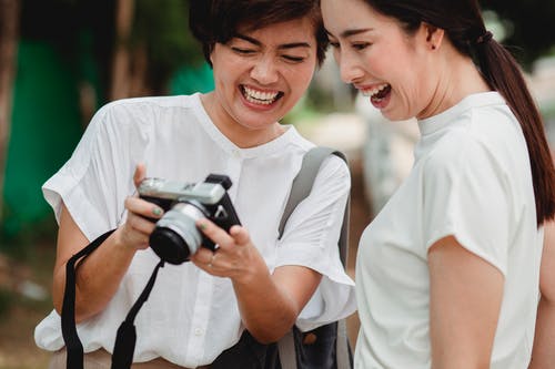 作物笑亚洲女友看着街上的相机拍照 · 免费素材图片