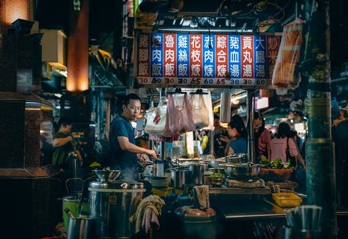 亚洲厨师烹饪食物与象形文字的明亮招牌下 · 免费素材图片