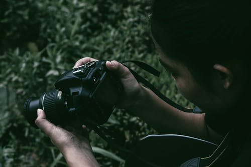 拿着黑单反相机的人 · 免费素材图片