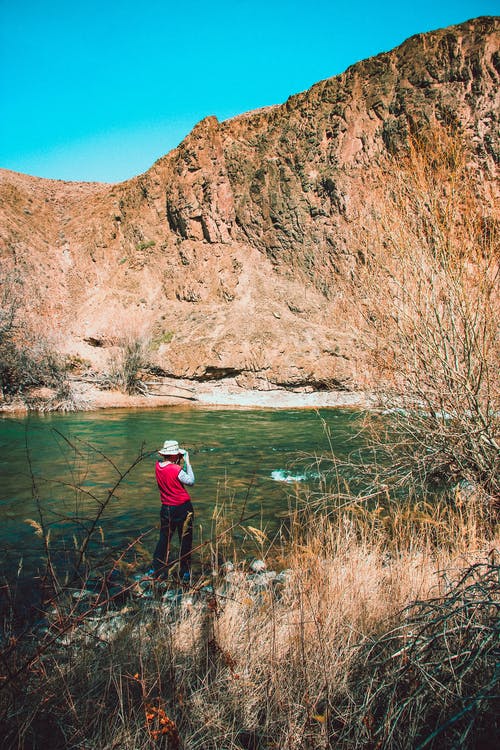 站在水边附近的红色和灰色长袖衬衫的人 · 免费素材图片