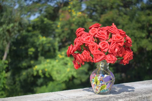 混凝土表面透明玻璃花瓶中的人造玫瑰 · 免费素材图片