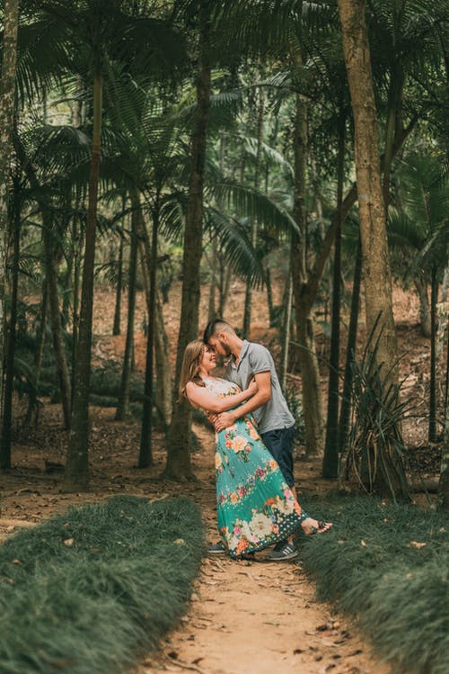 夫妻站在绿树环绕的土路上 · 免费素材图片
