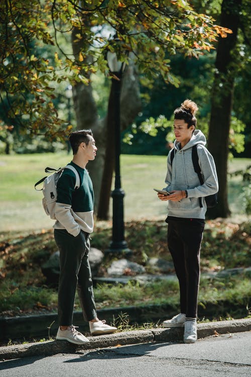时尚年轻多样男性千禧一代在绿色公园聊天在阳光灿烂的日子 · 免费素材图片