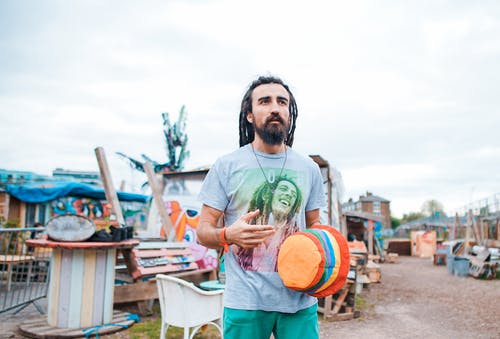 男子身穿蓝衫的脖子衬衫，拿着橙色的帽子 · 免费素材图片