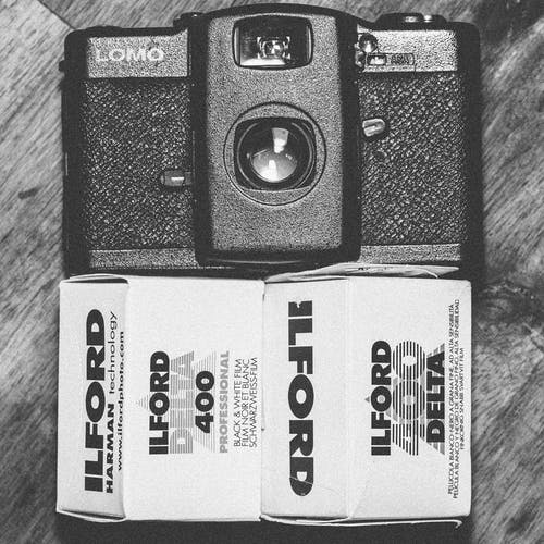 Ilford Delta 400黑白胶片盒旁边的黑色lomo紧凑型相机 · 免费素材图片