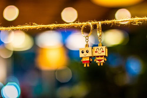 挂在俯瞰景灯的绳子上的两个男人和女人木制情侣钥匙扣 · 免费素材图片