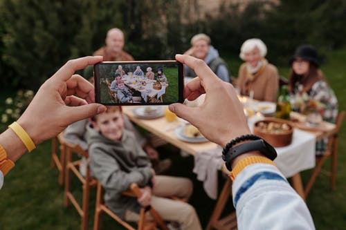 不可识别的人在智能手机上拍照的家庭晚餐 · 免费素材图片