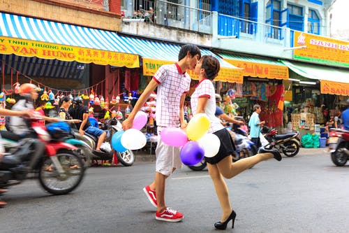 拿着气球的男人亲吻女人 · 免费素材图片
