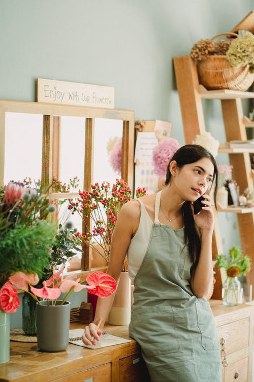 沉思的花店，谈手机在店里 · 免费素材图片